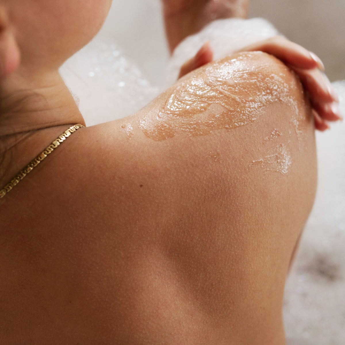 Vrouw gebruikt CÎME Wash & Scrub op de schouder in bad